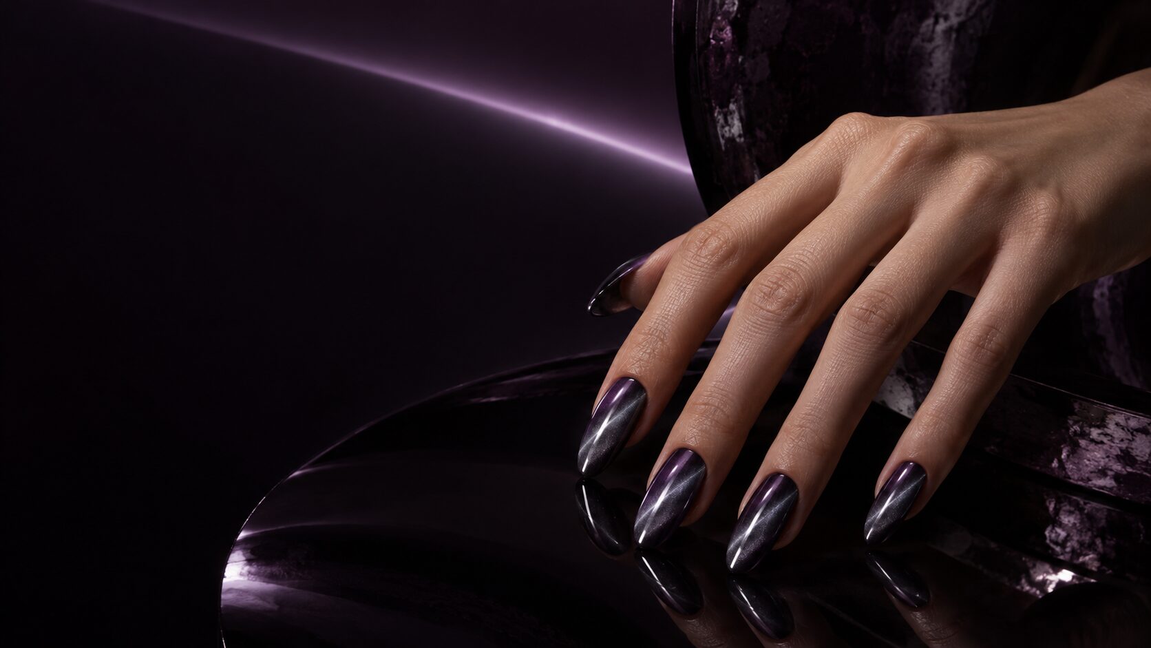 Smoked-violet magnetic cat-eye manicure in a dark editorial setting
